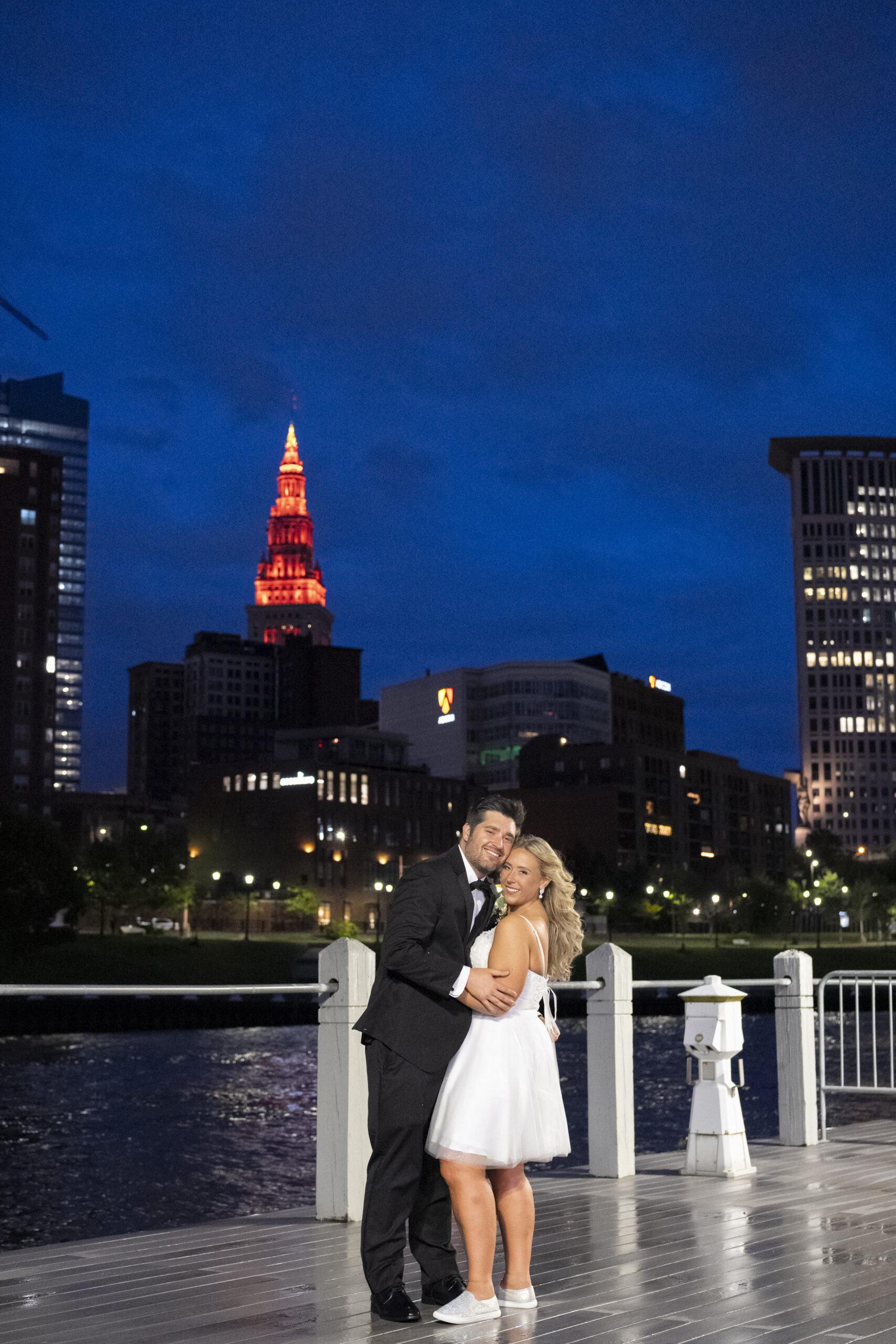 Bride and Groom at the end of the reception on the boardwalk outside windows on the river with cleveland and the the river in the background