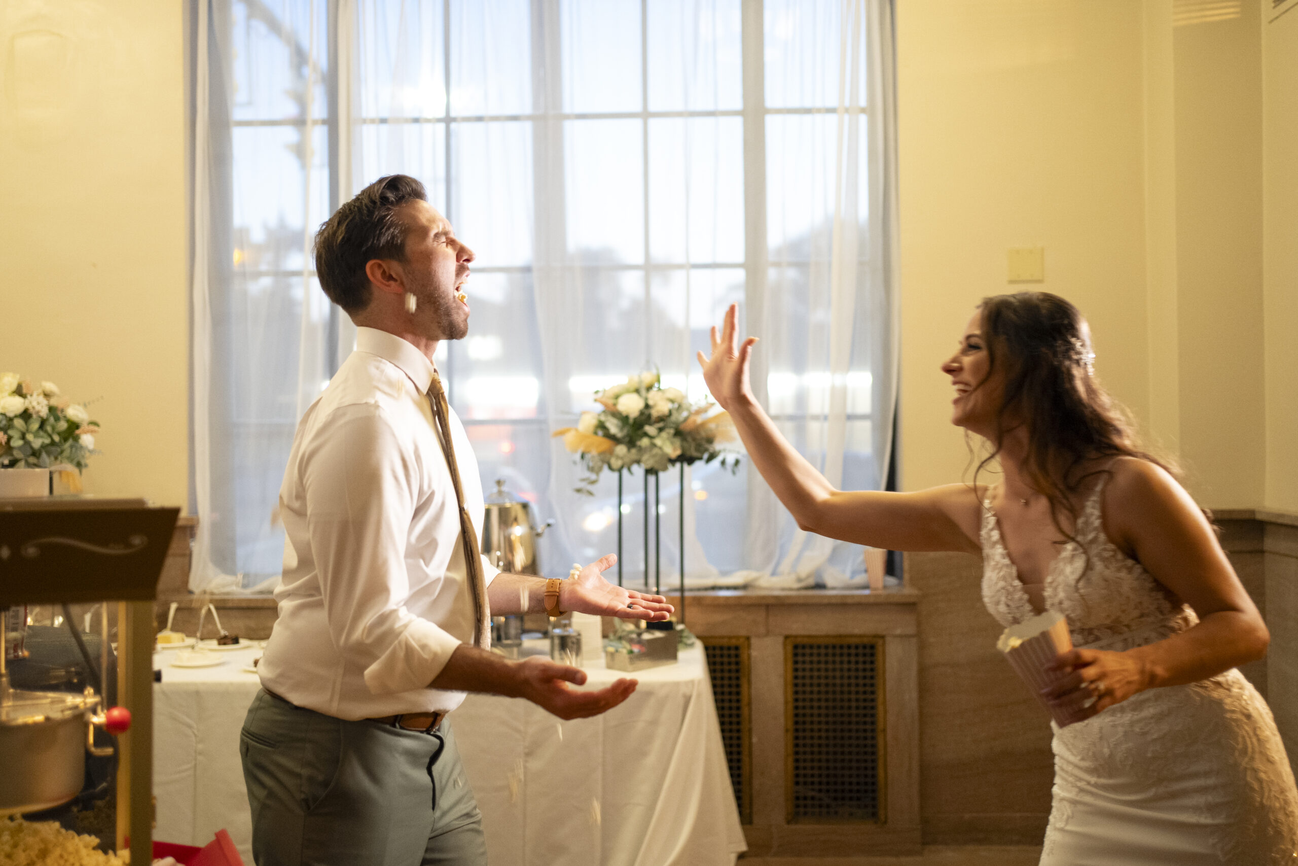 bride and groom tossing popcorn into each others mouths